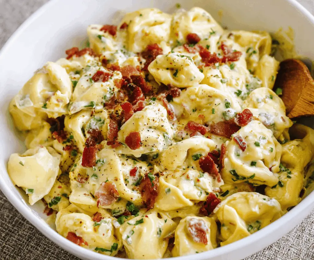 Creamy tortellini carbonara served in a white bowl, garnished with grated cheese and fresh herbs, showcasing a delicious Italian pasta dish