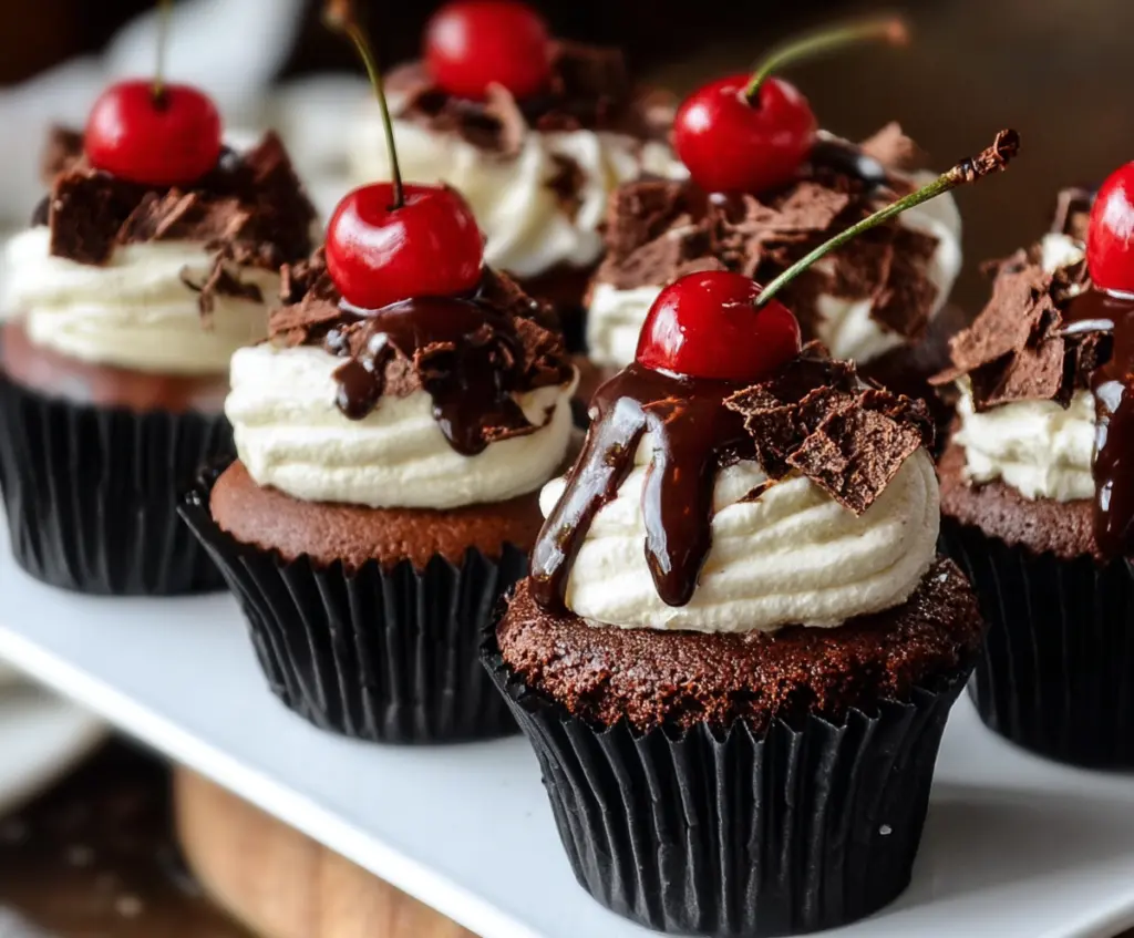 Delicious Black Forest Cupcakes topped with whipped cream and cherries, perfect for dessert lovers.